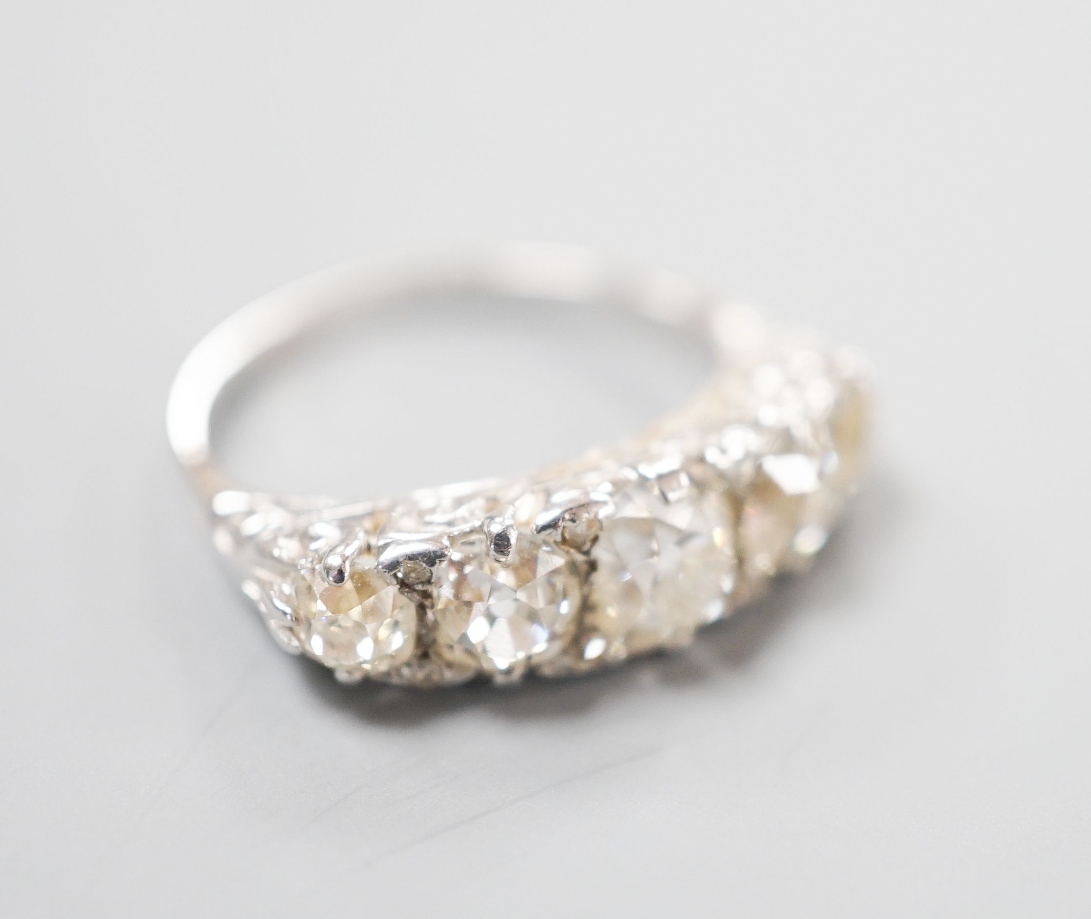 A white metal and graduated five stone old cut diamond set half hoop ring, with diamond chip spacers, size L, gross weight 3.7 grams.